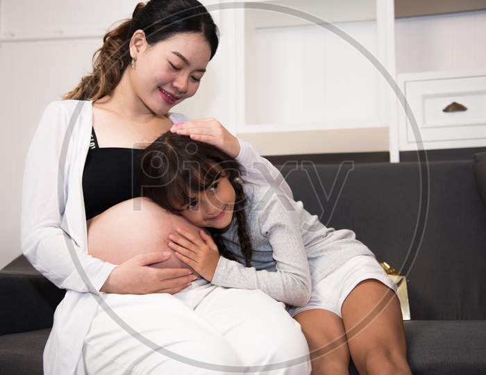 The Daughter Is Listening To Her Mother Belly When New Born Kicking. Family And Pregnant Concept. Baby And Interior Theme