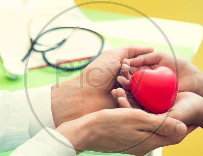 Doctor Hands Holding And Giving Red Massage Heart To Patient Little Children For Recover From Sickness. Hospital And Healthcare Concept. Cpr And Cardiology From Heart Attack And Disease. Heart Donate