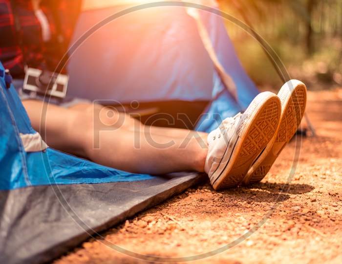 Close Up Of Woman Strecthing Feet With Shoe With Nature Background. Tourist Woman Resting In Camping Tent. People And Lifestyles Concept. Holiday And Vacation Theme. Camera Element