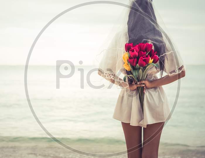 Asian Woman Holding Flowers In Behind And Waiting For Someone Make Her Happy. Lonely And Single Woman Concept. Sadness And Soulmate Concept. Dark Ton Film Filter. Heart Broken And Wedding Theme.