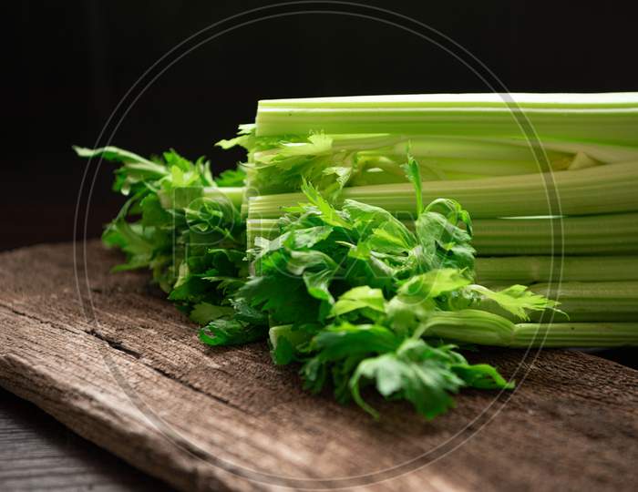 Bunch Of Fresh Celery Stalk On Wooden Table With Leaves On Black Background. Food And Ingredients  Of Healthy Vegetable. Freshness Herbal And Low Calories For Dieting With Plenty Of Vitamin