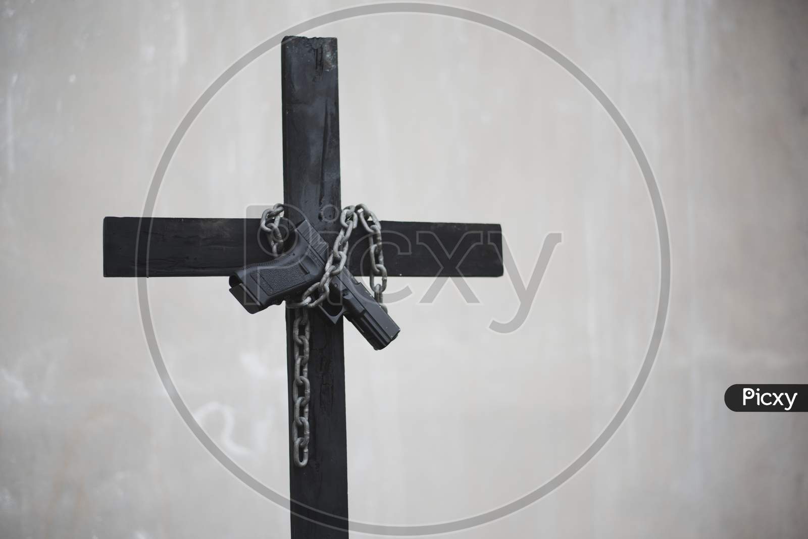Black Cross With Chain And Handgun On White Grunge Wall. Object And Weapon Concept. Christian Religion Theme. Halloween And Criminal Theme. Copy Space On Right.