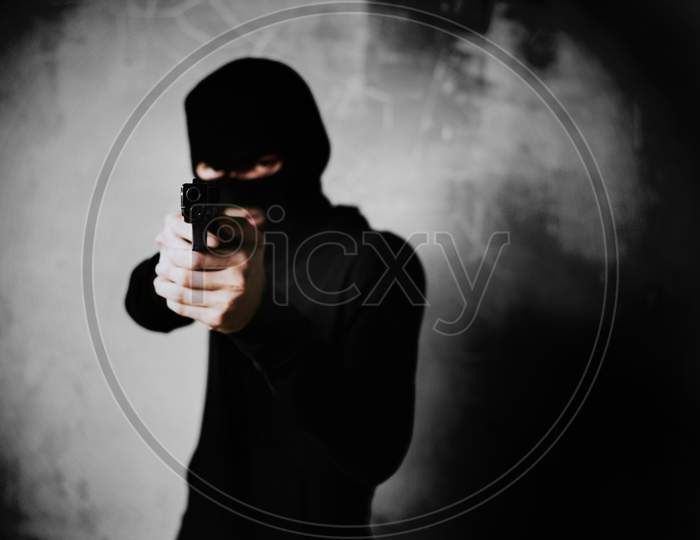 Terrorist Shooting With His Mini Gun Weapon With Grunge Room Wall Background. Criminal And Dangerous Illegal People Concept. Terrorist And War Theme. Dark Tone And High Contrast Use