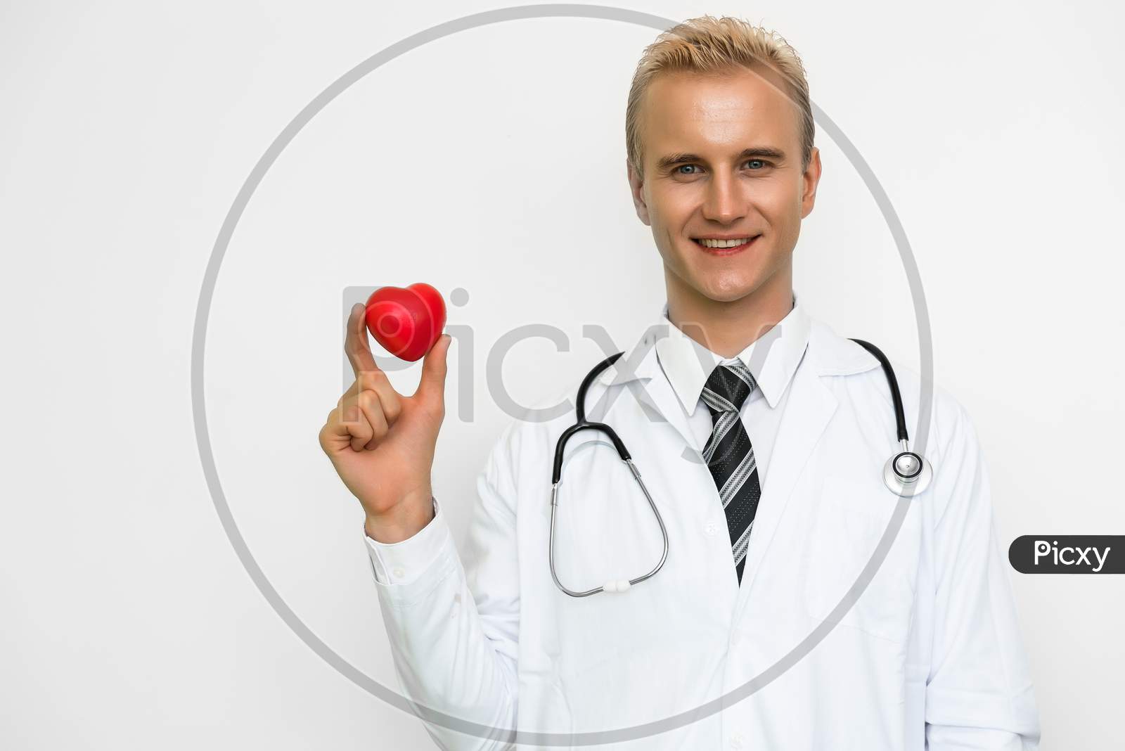 Handsome Male Doctor Holding Red Heart And Smiling. Healthcare And Medical Concept. Happiness People And Lifestyle Theme.