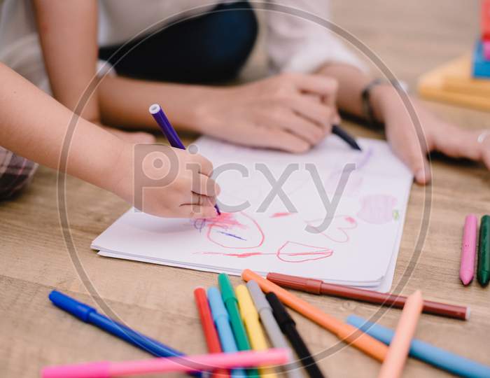 Closed Up Hands Of Mom Teaching Little Children To Drawing Cartoon In Art Class With Color Pen. Back To School And Education Concept. Family And Home Sweet Home Theme. Preschool Kids Theme