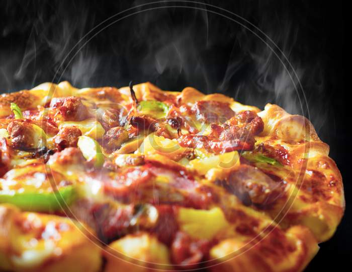 Pizza With Cheese Ham Bacon And Pepperoni On Isolated Black Background With Hot Steaming Smoke. Food And Cooking Concept. Lunch Time Serve And Hungry Theme. Pizza Delivery Service To Home Advertising