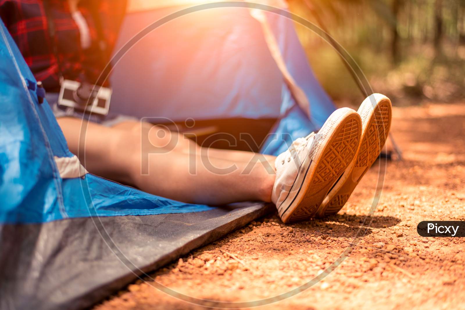 Close Up Of Woman Strecthing Feet With Shoe With Nature Background. Tourist Woman Resting In Camping Tent. People And Lifestyles Concept. Holiday And Vacation Theme. Camera Element
