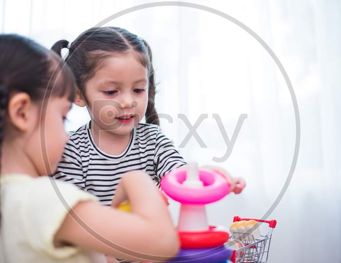 Two Little Girls Playing Toy Hoops In Home Together. Education And Happiness Lifestyle Concept. Funny Learning And Children Development Theme. Smile Faces