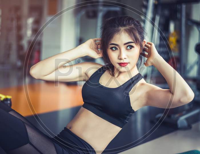 Side View Of Asian Fitness Girl Doing Crunch Twist At Fitness Gym. Sports And Workout Concept. Fitness Gym And Beauty Theme.