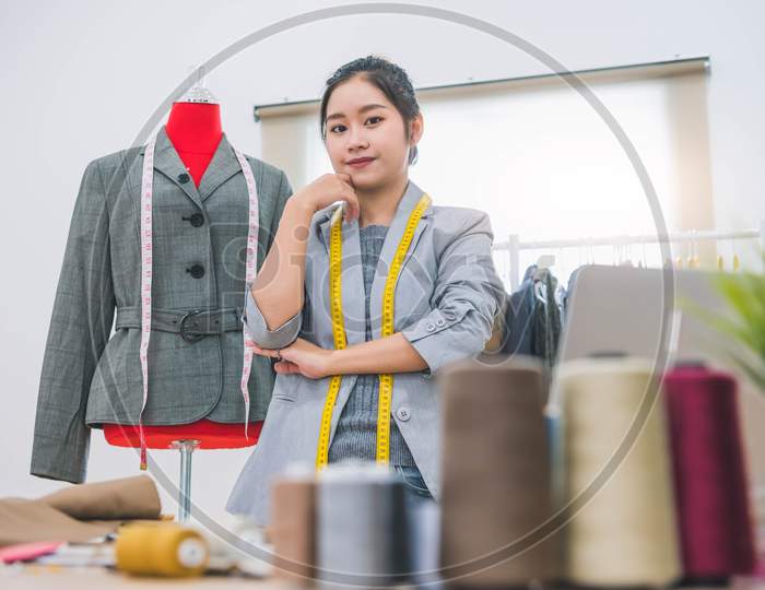 Fashion Designer Stylist In Business Owner Workshop. Tailor And Sewing Concept. Portrait Of Happy Casual Trendy Fashion Designer Businesswoman In Studio Looking Camera. Business Job And Occupation