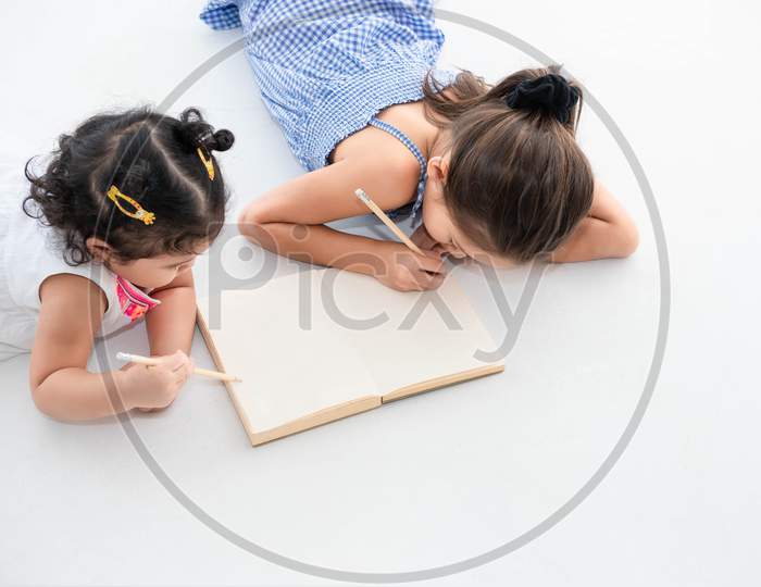 Top View Of Happy Two Sister Drawing In Sketch Book Together At Home Or Nursery. People Lifestyle And Kids Play. Education And Children Concept. Diverse Ethnicity And Ages. Back To School Theme