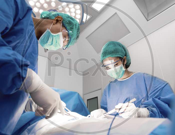 Doctors And Nurse With Tools In Hands Making Surgery In Operation Room. Health Care And Hospital Concept