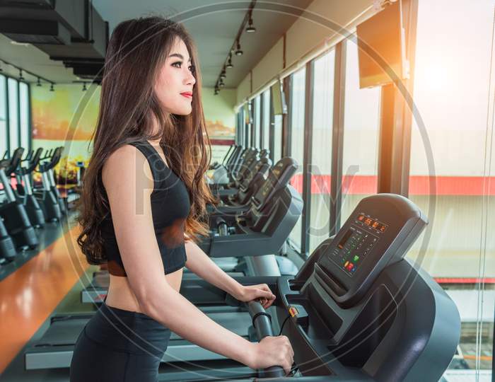 Asian Sport Woman Walking Or Running On Treadmill Equipment In Fitness Workout Gym. Sport And Beauty Concept. Workout And Strength Training Theme. Cardio And Diet Theme