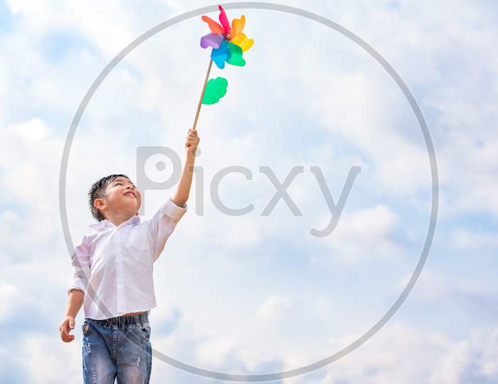 Boy Holding Colorful Pinwheel In Windy At Outdoors. Children Portrait And Kids Playing Theme.