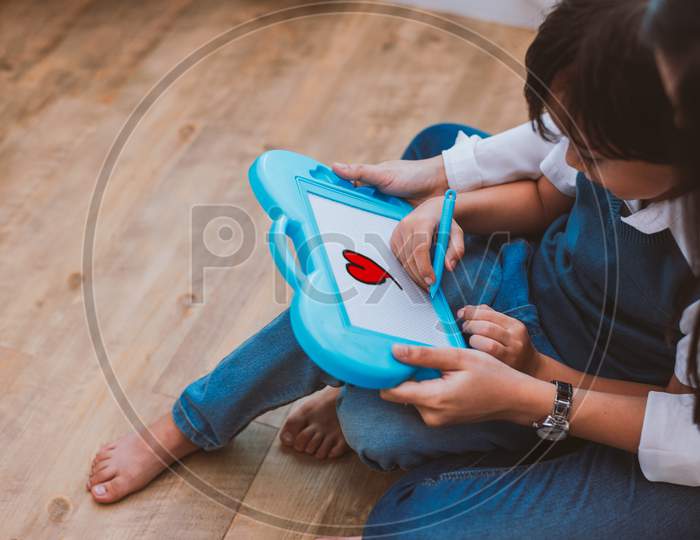 Asian Mom Teaching Cute Boy To Drawing Red Heart In Board With Color Pen. Back To School And Education Concept. Family And Home Sweet Home Theme. Preschool Kids Theme. Top View Angle