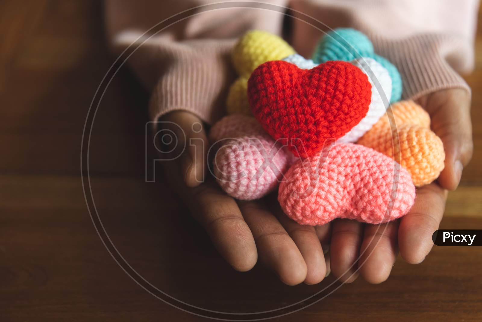 Mixed Colors Yarn Heart On Giving Hands. Close Up Of Colorful Handmade. Heart Donation Concept. Valentine  Love Forever Theme