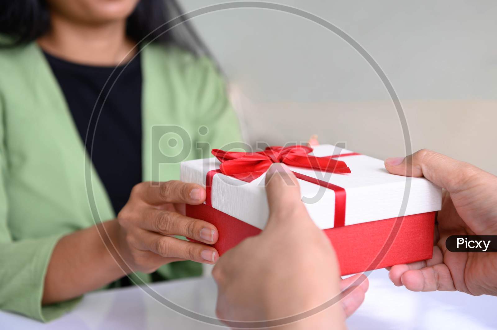 Closeup Of Hands Giving Gift Box In Christmas Day And New Year Festival To Each Other With Woman Background. Holiday And Event. Surprising Giftbox In Dating On End Year Party. People Lifestyle Concept