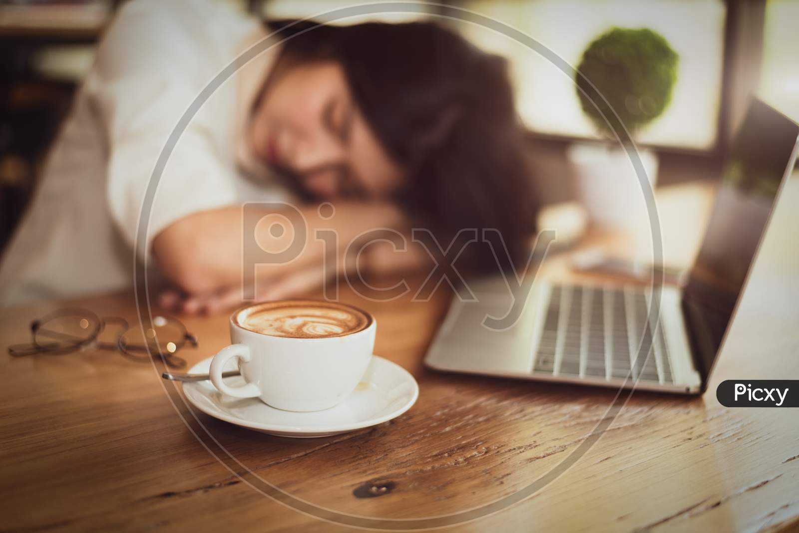 Close Up Of Full Of Coffee In Coffee Cup With Business Woman Tired From Working And Laptop Computer Background. Relax Sleeping And Healthy Concept. Business People And Overtime Workload Theme