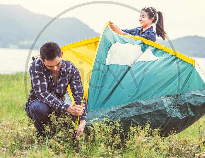 Two Asian Couples Prepare Pitch Camping Tent To Stay Outdoors Meadow Overnight For Honeymoon Camping Picnic. People Lifestyle And Valentine Day Love Concept. Nature Travel Vacation Relaxation Activity