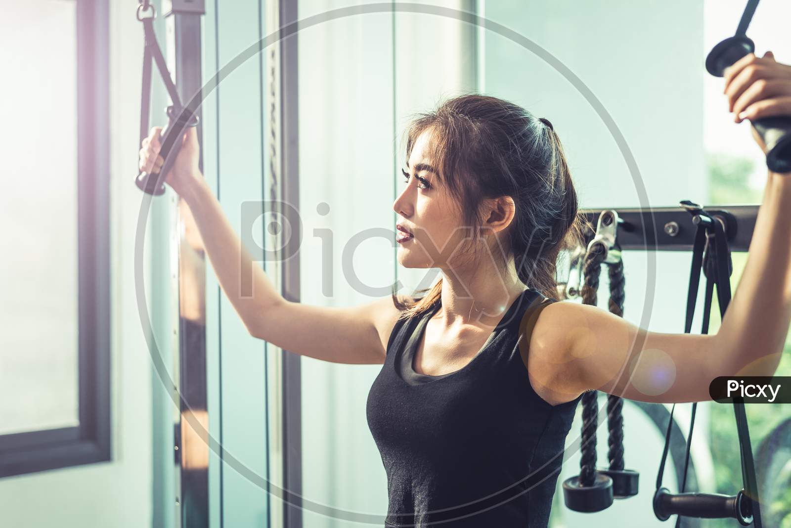 Asian Young Woman Doing Elastic Rope Exercises At Cross Fitness Gym. Strength Training And Muscular Beauty And Healthy Concept. Sport Equipment And Sport Club Center Theme.