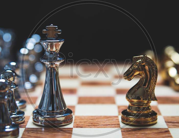 Strategy Of Strong Leadership As King And Weak Leadership As Horse Facing Each Other In Wooden Chess Board. Business Marketing Of Competition Trade Partners Tactics Concept On Black Background