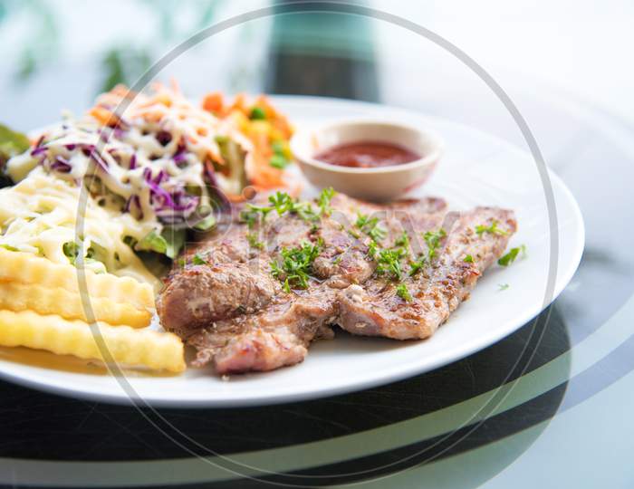 Pork Chop Steak With Salad And Gravy Sauce In Dish. Food And Vegetable Concept. Restaurant And Menu Theme.