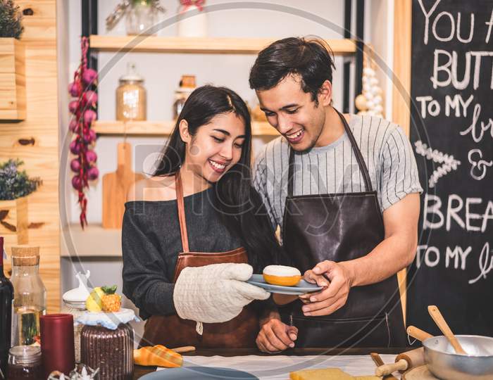 Young Couples Making Bakery Donuts And Bread At Bakery Shop As Business Ownership Entrepreneur. Husband And Wife Cooking Together In Kitchen. Happiness People And Lifestyle Relationship Concept