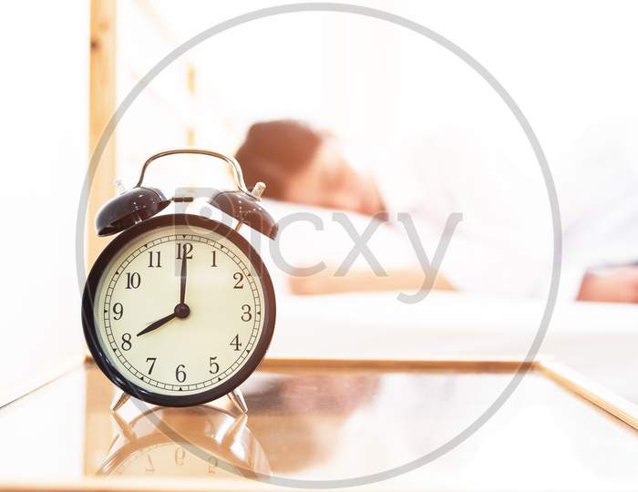 Alarm Clock With Sleeping Woman In Bed Room. Lazy Time In Holiday Concept.