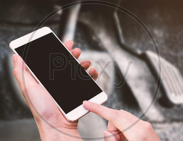 Woman Hold Smart Phone And Touch Button By Hand With Blank Screen For Advertisement, Accelerator And Brake Of Car Background ,Technology And Safety Concept