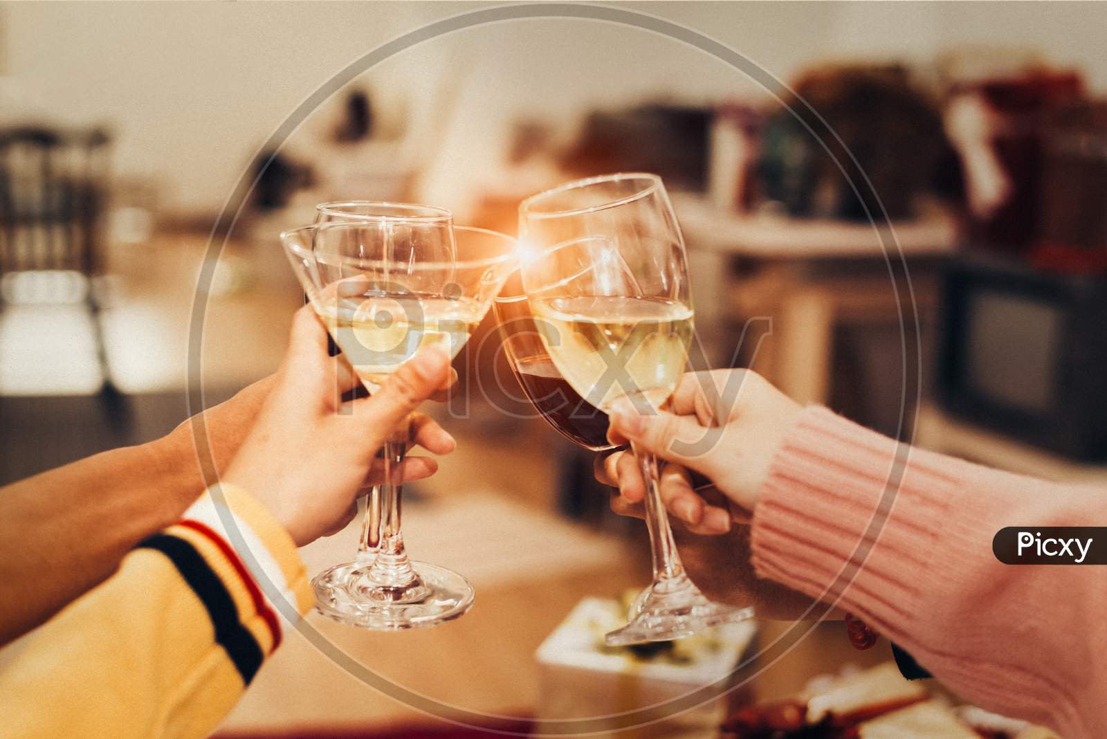 Hands Of People Celebrating New Year Party In Home With Wine Drinking Glasses And Present Background. New Year And Christmas Party Concept. Happiness And Friendship And Funny Together. Clinking Glass