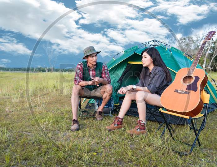 Two People Talking Near Camping Tent In Meadow Field. Male And Female Traveler Looking At Attraction View Point. Couples Adventure At Outdoors Together. People And Lifestyles Concept