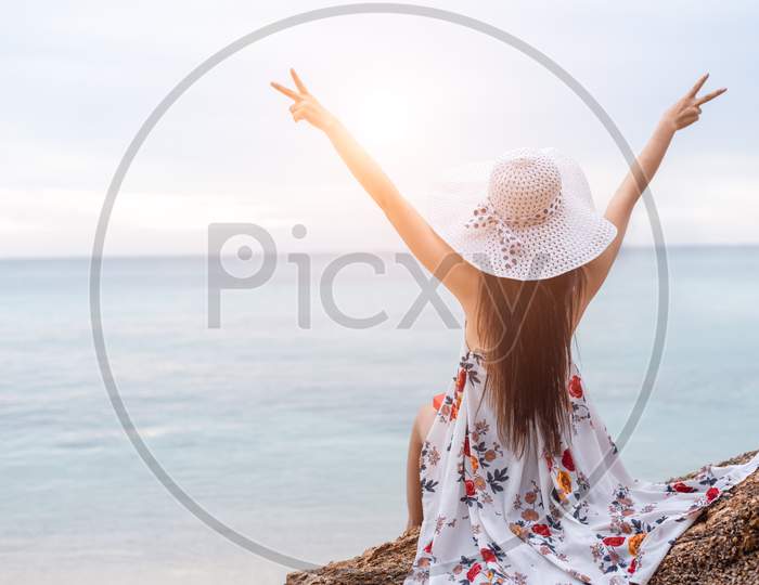 Beauty Woman Doing Cheerful Gesture Beside The Beach. Woman Raise Two Hands And Breathing Fresh Air Happily. People And Lifestyles Concept. Travel And Vacation Theme. Back View
