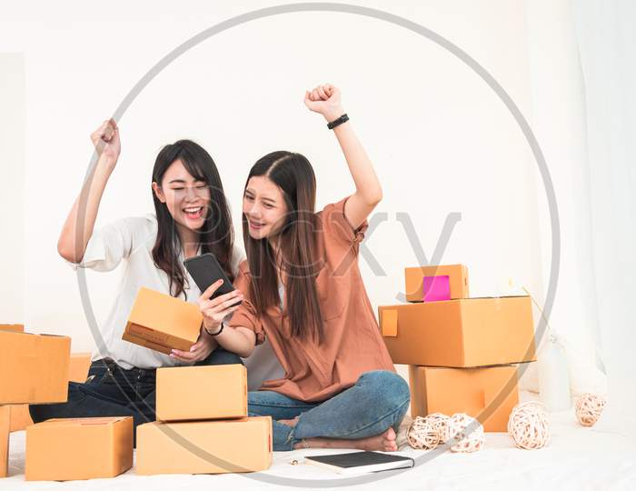 Two Young Asian Woman Startup Small Business Entrepreneur Sme Distribution Warehouse With Parcel Mail Box. Owner Home Office. Online Marketing And Product Packaging And Delivery Service. Happy Gesture