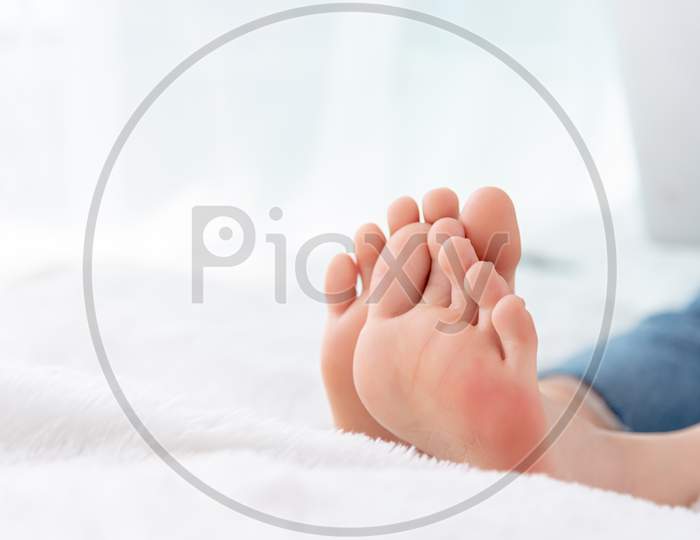 Closeup Woman Feet Skin Wearing Jeans On White Bed. Healthcare And Health Medical Concept.