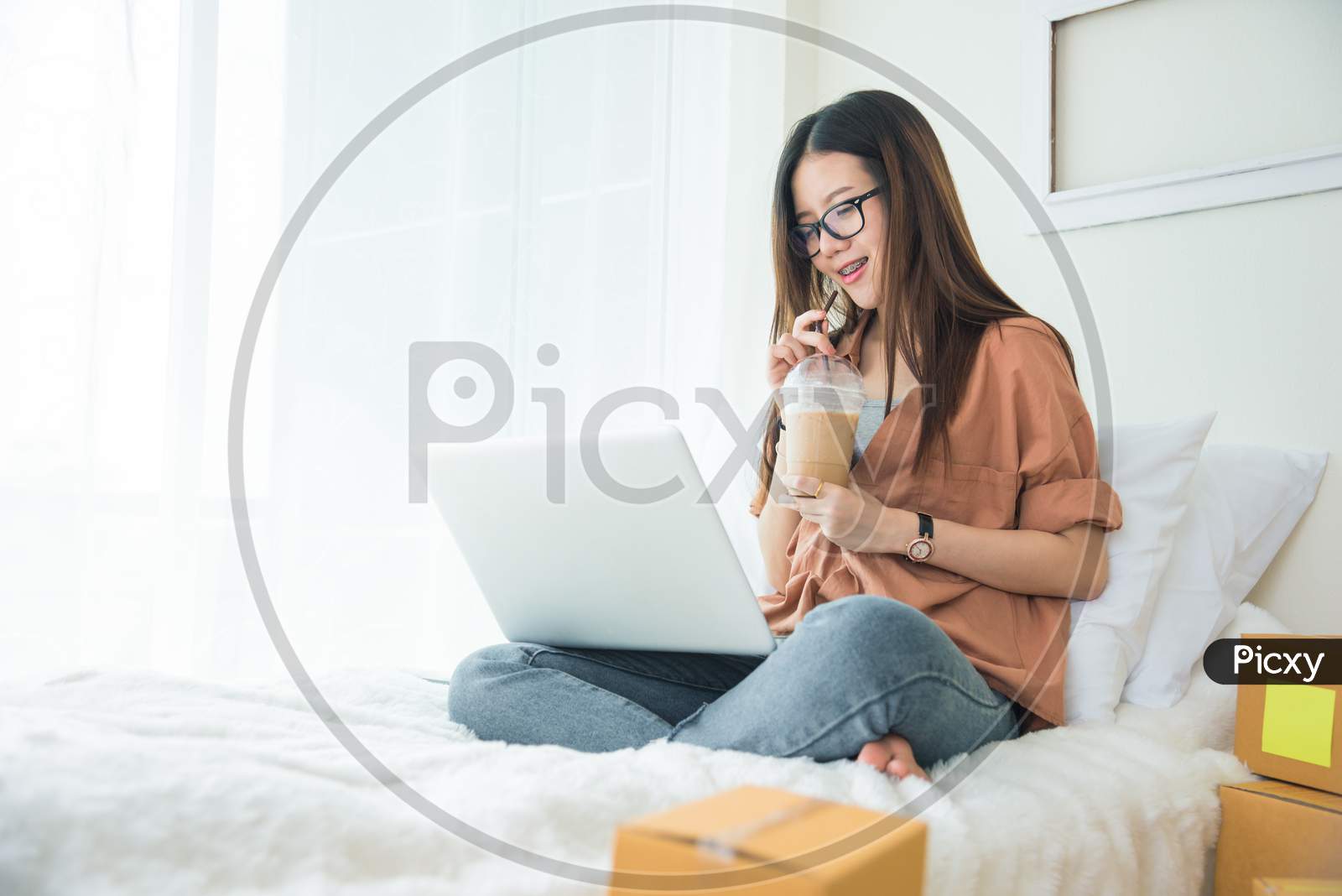 Beauty Asian Woman Using Laptop And Drinking Coffee On Bed. Business And Technology Concept. Delivery And Online Shopping Concept. Post And Service Theme.