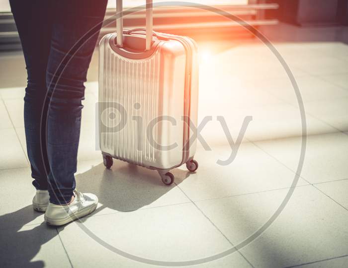 Close Up Woman And Suitcase Trolley Luggage In Airport. People And Lifestyles Concept. Travel And Business Trip Theme. Woman Wearing Jeans Going On Tour And Traveling Around The World By Alone.