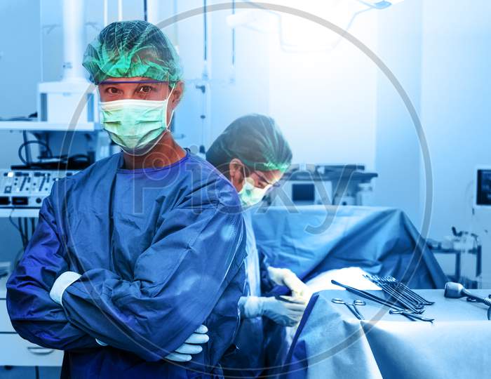 Professional Doctor And Nurse In Operation Room. Portrait And Healthcare Concept. Teamwork And Success Concept.Working People In Hospital And Plastic Surgery For Beauty Theme. Blue Filter Background.