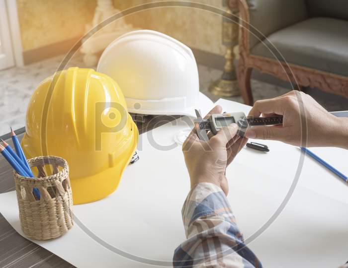 Construction Engineer Measuring With Vernier Caliper. Business And Technology Concept. Safety Helmet And Drawing Paper Elements. Civil And Drawing Sketch Theme.