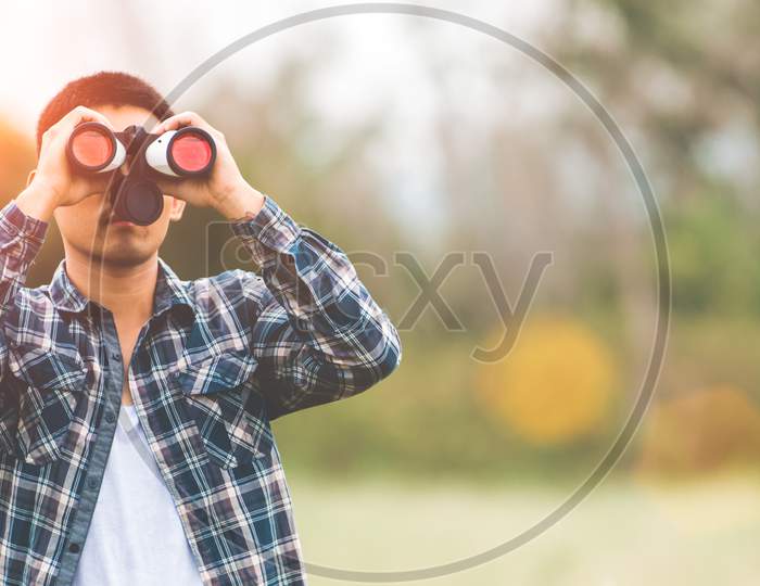 Man With Binoculars Telescope In Forest Looking Destination As Lost People Or Foreseeable Future. People Lifestyles And Leisure Activity Concept. Nature And Backpacker Traveling Jungle Background