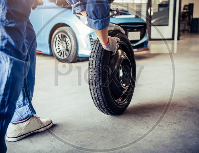 Car Mechanics Changing Tire At Auto Repair Shop Garage. Transportation And Business Working People Concept. Automobile Technician Maintenance Vehicle By Customer Claim Order. Wheel Repair Service