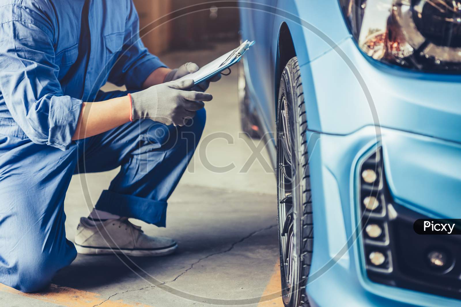Asian Car Mechanic Technician Holding Clipboard And Checking To Maintenance Vehicle By Customer Claim Order In Auto Repair Shop Garage. Wheel Tire Repair Service. People Occupation And Business Job