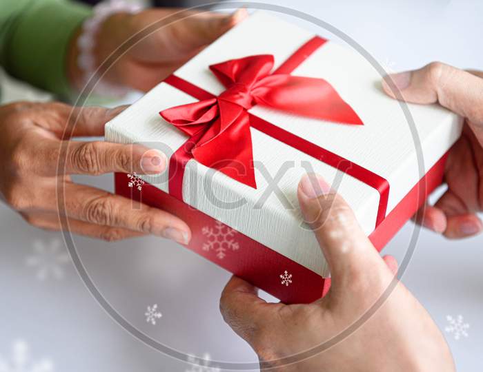 Closeup Of Hands Giving Gift Box In Christmas Day And New Year Festival To Each Other. Holiday And Event. Surprising Giftbox In Dating On End Year Party. People Lifestyle And Object Concept.