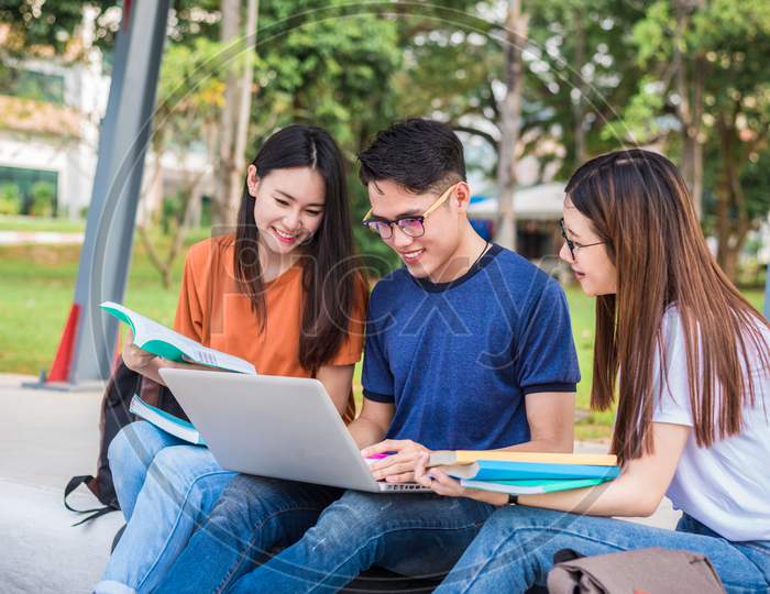 Three Asian Young Campus Students Enjoy Tutoring And Reading Books Together. Friendship And Education Concept. Campus School And University Theme. Happiness And Funny Of Learning In College