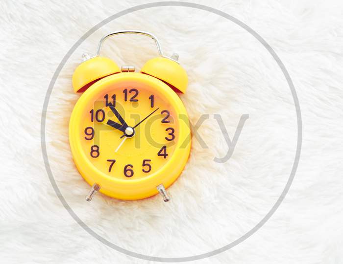 Yellow Alarm Clock On White Wool. Late And Lazy Time Concept. Morning In Holiday Theme. Around 10 O Clock