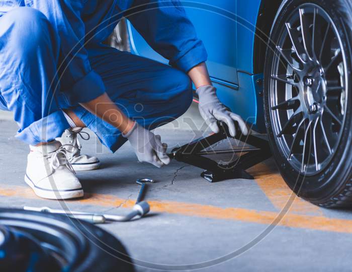 Car Mechanics Changing Tire At Auto Repair Shop Garage. Transportation And Business Working People Concept. Automobile Technician Maintenance Vehicle By Customer Claim Order. Wheel Repair Service