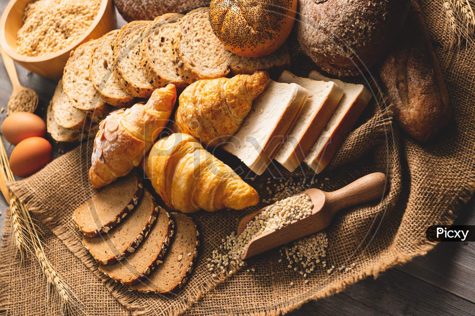 Different Kinds Of Bread With Nutrition Whole Grains On Wooden Background. Food And Bakery In Kitchen Concept. Delicious Breakfast Gouemet And Meal. Top View Angle