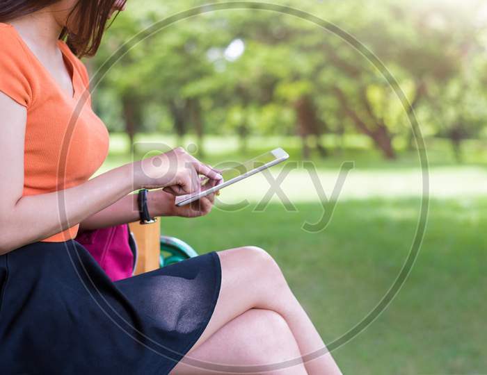 Beauty Woman Using Tablet In The Park. Technology And Lifestyles Concept. Outdoor And Nature Theme.