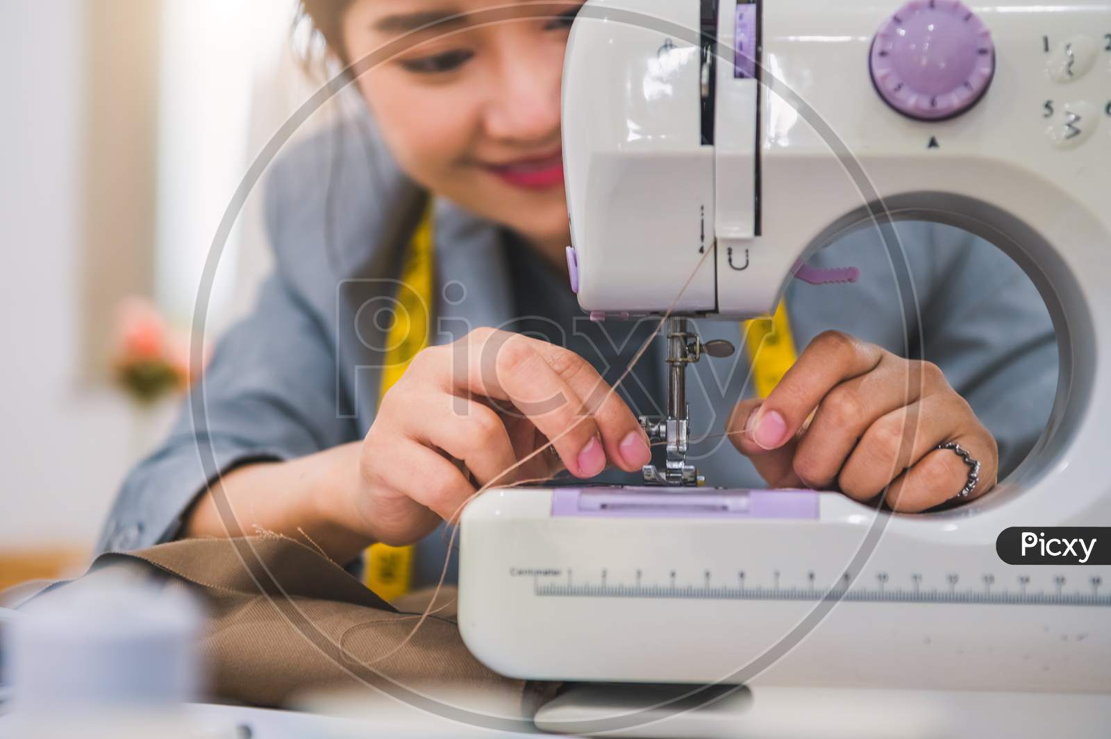 Closeup Of Attractive Female Fashion Designer Hand Working Workshop With Sewing Machine. Stylish Fashionista Woman Creating New Cloth Design Collection. Tailoring And Sewing Lifestyle And Occupation