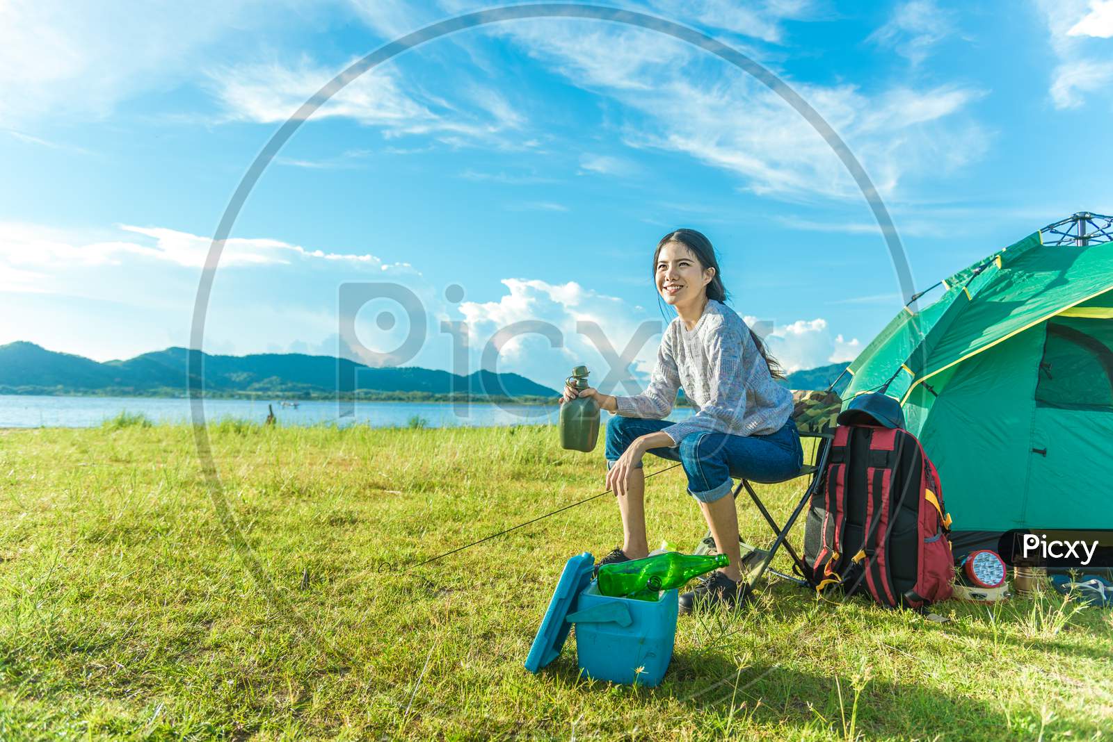Happy Woman Drinking Alcohol While Camping At Meadow. People And Lifestyles Concept. Travel And Adventure Theme. Female Tourist Portrait