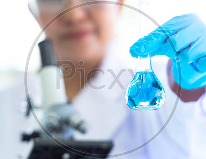 Female Scientist Hold And Showing Laboratory Test Tubes And Solution With Stethoscope. Science And Medical Background. Scientist Research And Analysis Biotechnology Concept. Selective Focus Blue Flask